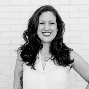 A woman standing in front of a brick wall.