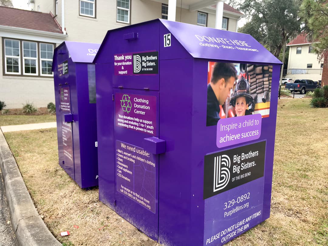 Two purple boxes are sitting in the grass.