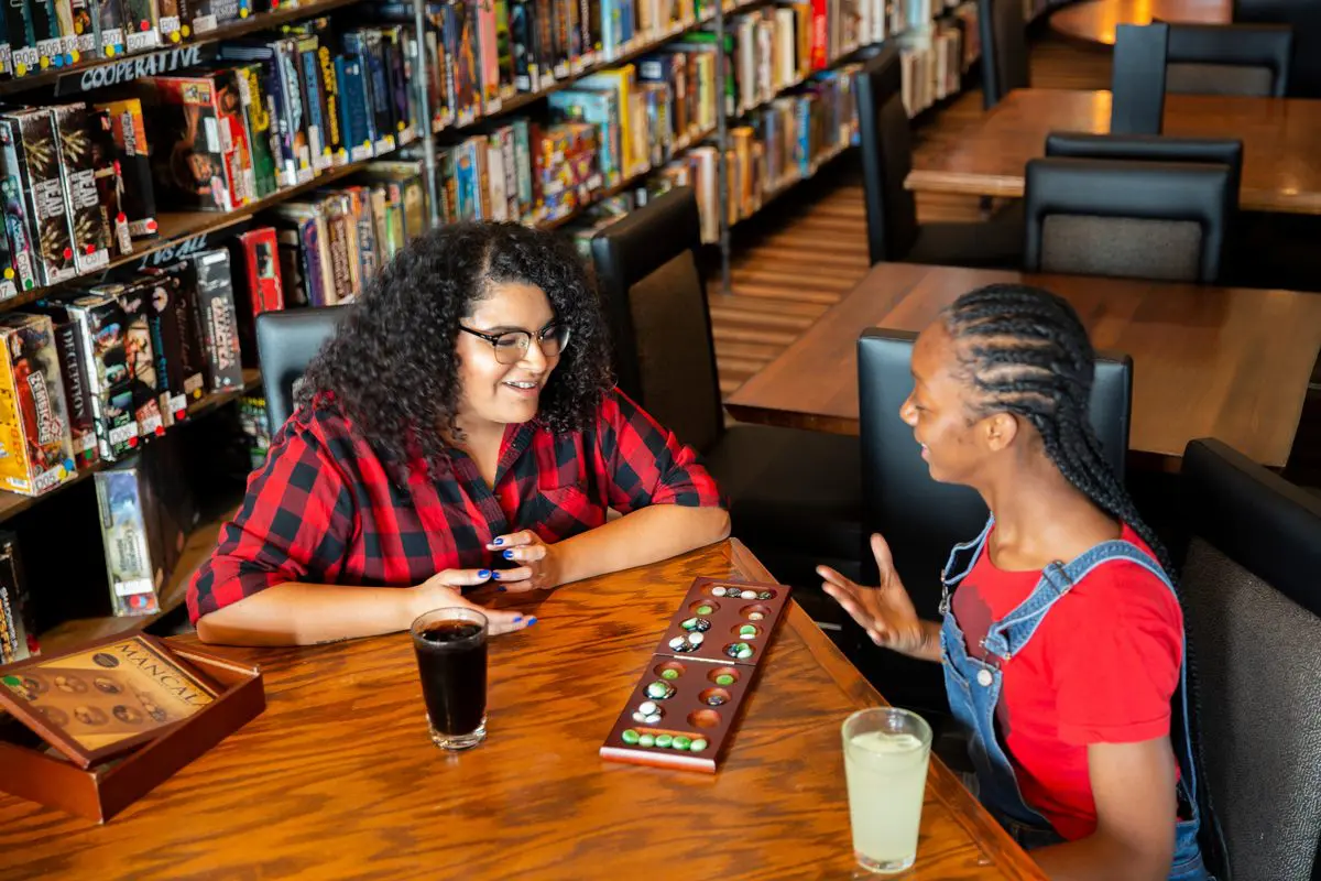 Two women sitting at a table in front of bookshelves.