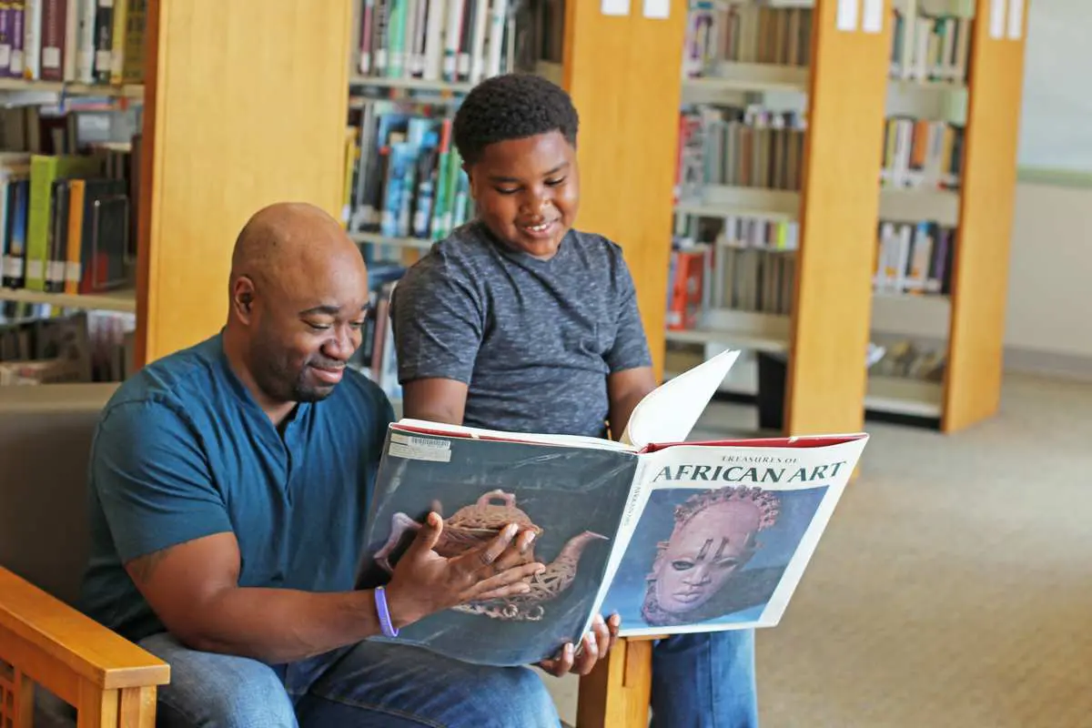 A man and woman reading books in the library.