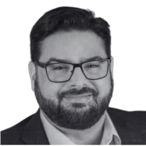 Man with glasses and beard, smiling.