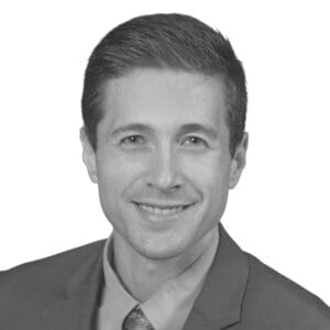 Man in suit smiling, grayscale portrait photo.